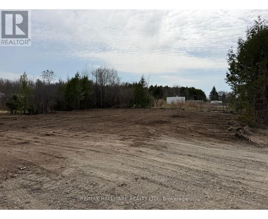 A dirt field with trees and a building in the distance.