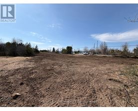 A barren land with a clear sky and some trees in the distance.