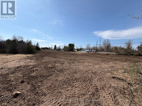 A barren land with a clear sky and some trees in the distance.