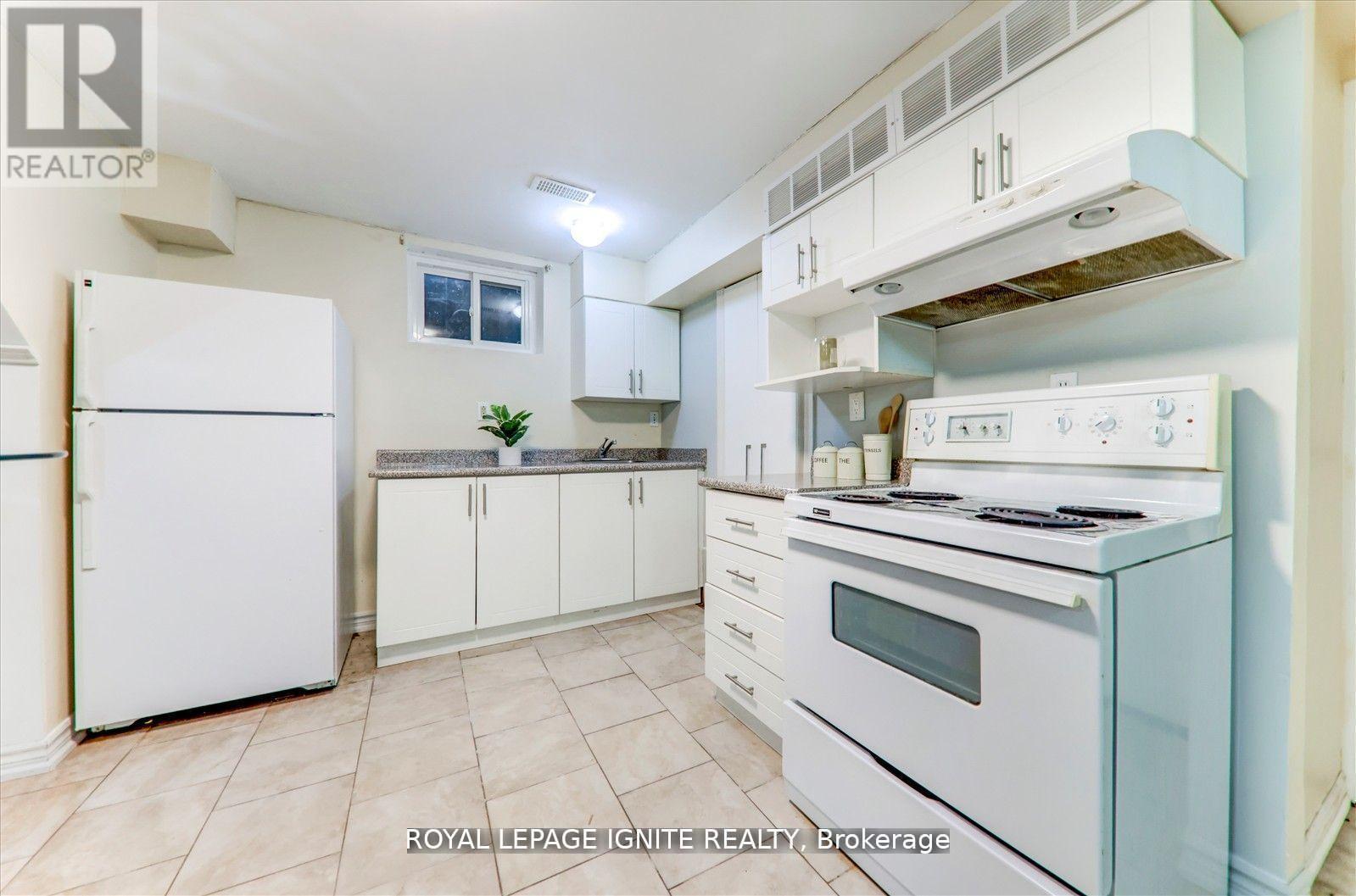 A white kitchen with a refrigerator, oven, and cabinets.