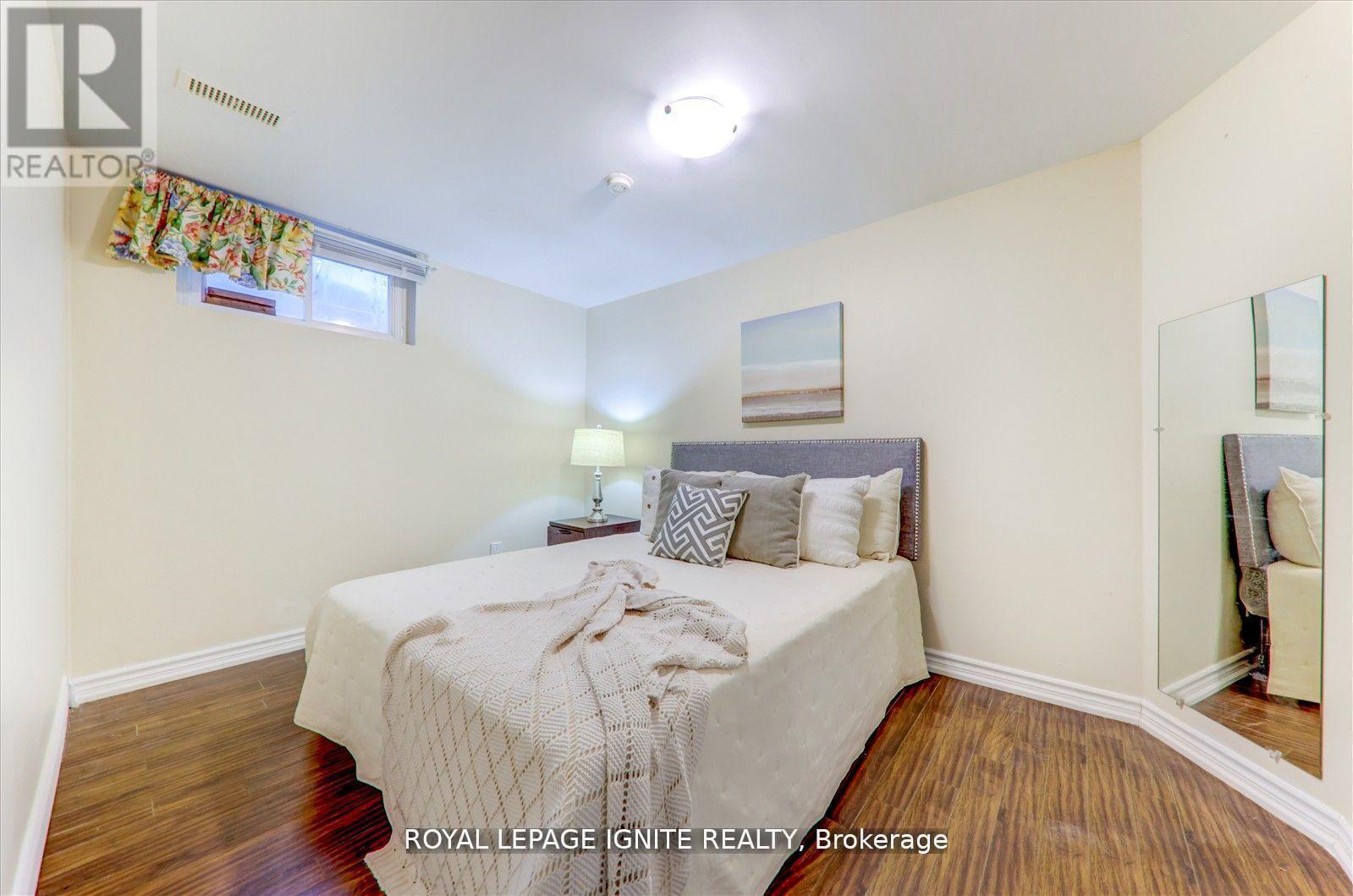 A bedroom with a bed, nightstand, and a mirror on the wall.