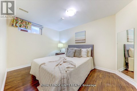 A bedroom with a bed, nightstand, and a mirror on the wall.