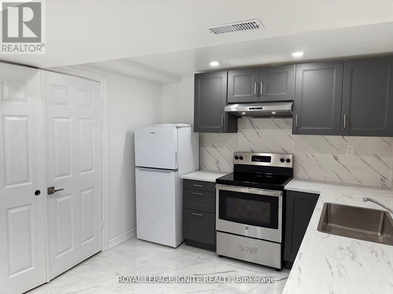 A kitchen with white appliances and black cabinets.