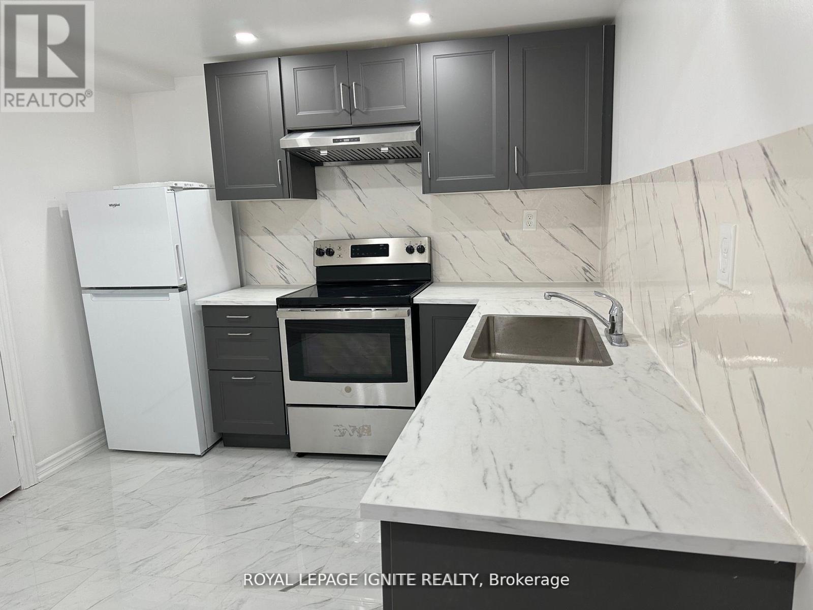 A kitchen with a white refrigerator, stove, and sink.