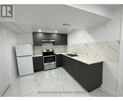 A kitchen with black cabinets and a white refrigerator.