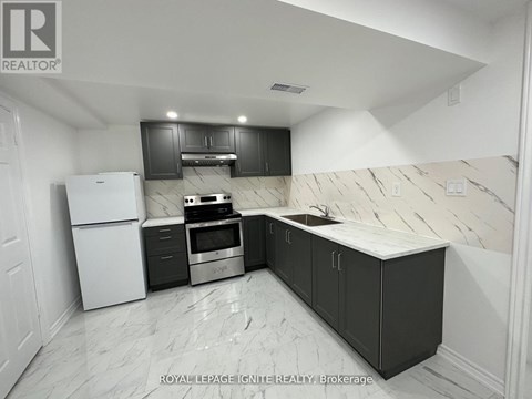 A kitchen with black cabinets and a white refrigerator.