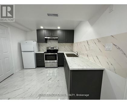 A kitchen with a white fridge, black cabinets, and a marble countertop.