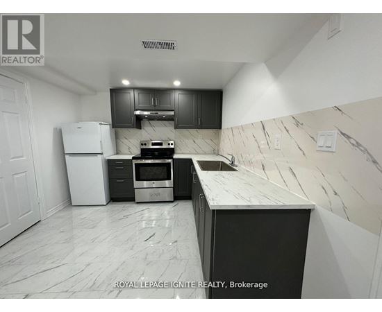 A kitchen with a white fridge, black cabinets, and a marble countertop.