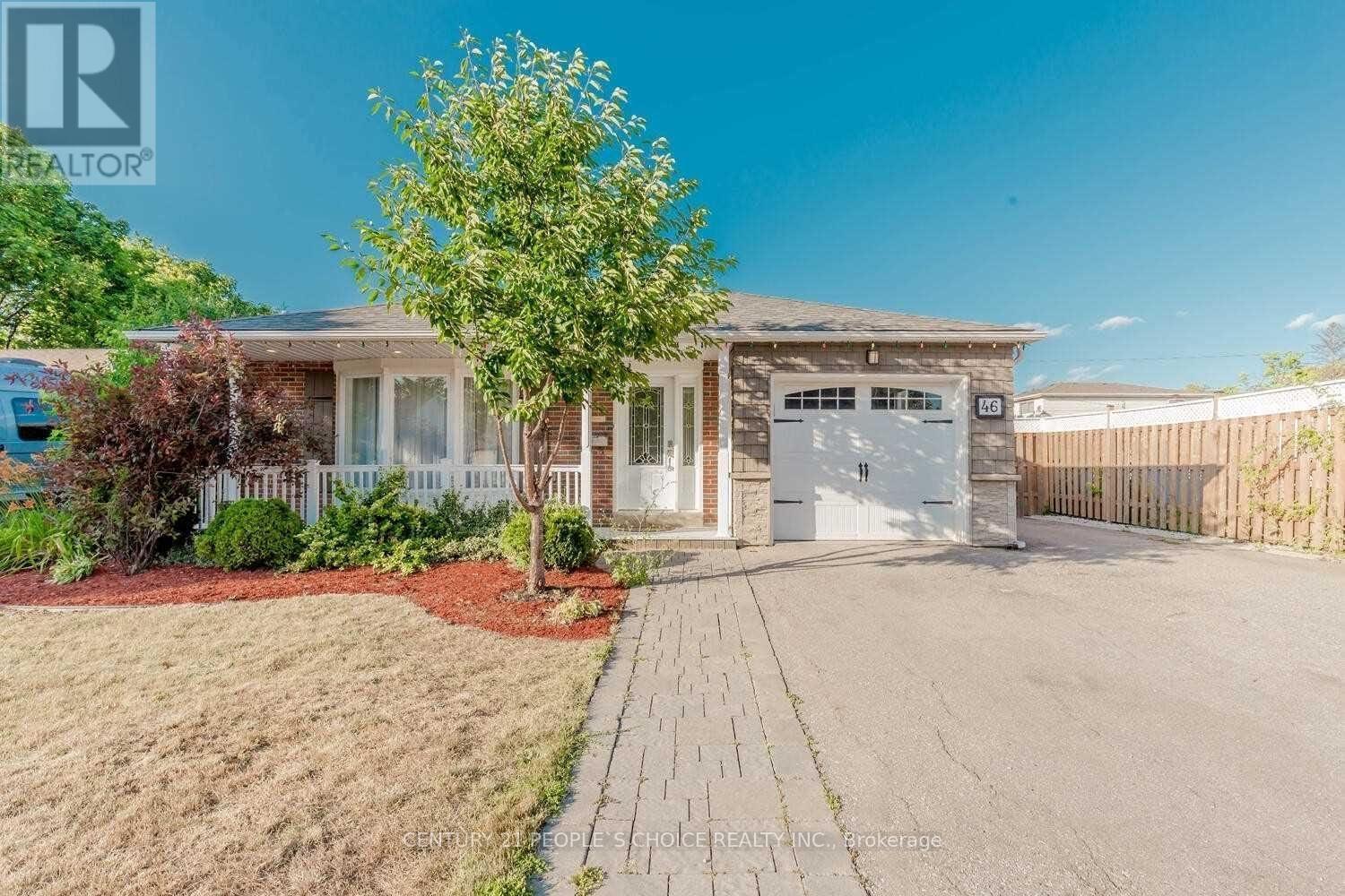 A house with a driveway and a tree in front of it.