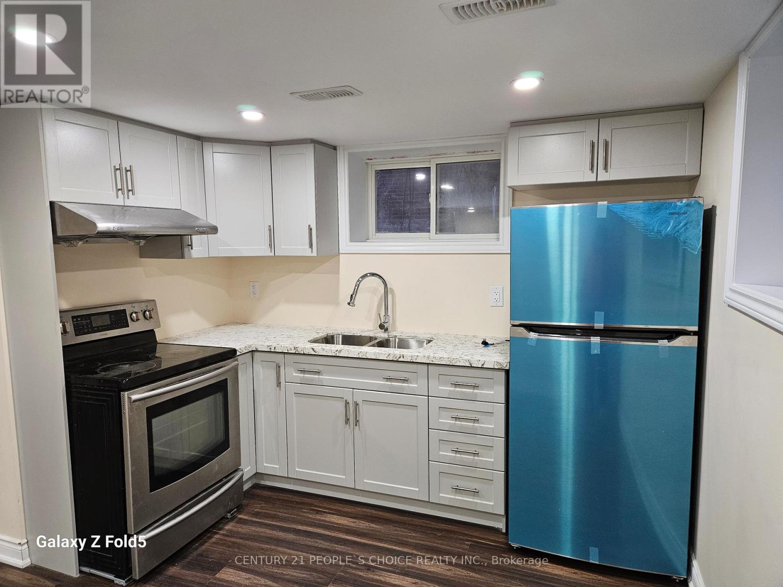 A kitchen with a blue refrigerator and white cabinets.
