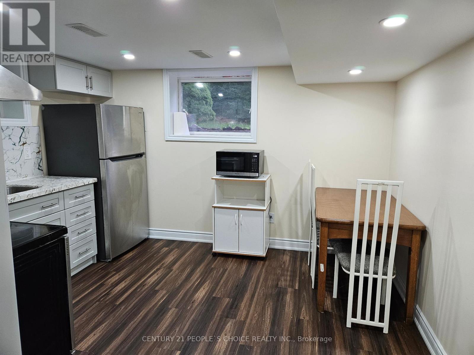 A kitchen with a refrigerator, oven, and microwave.