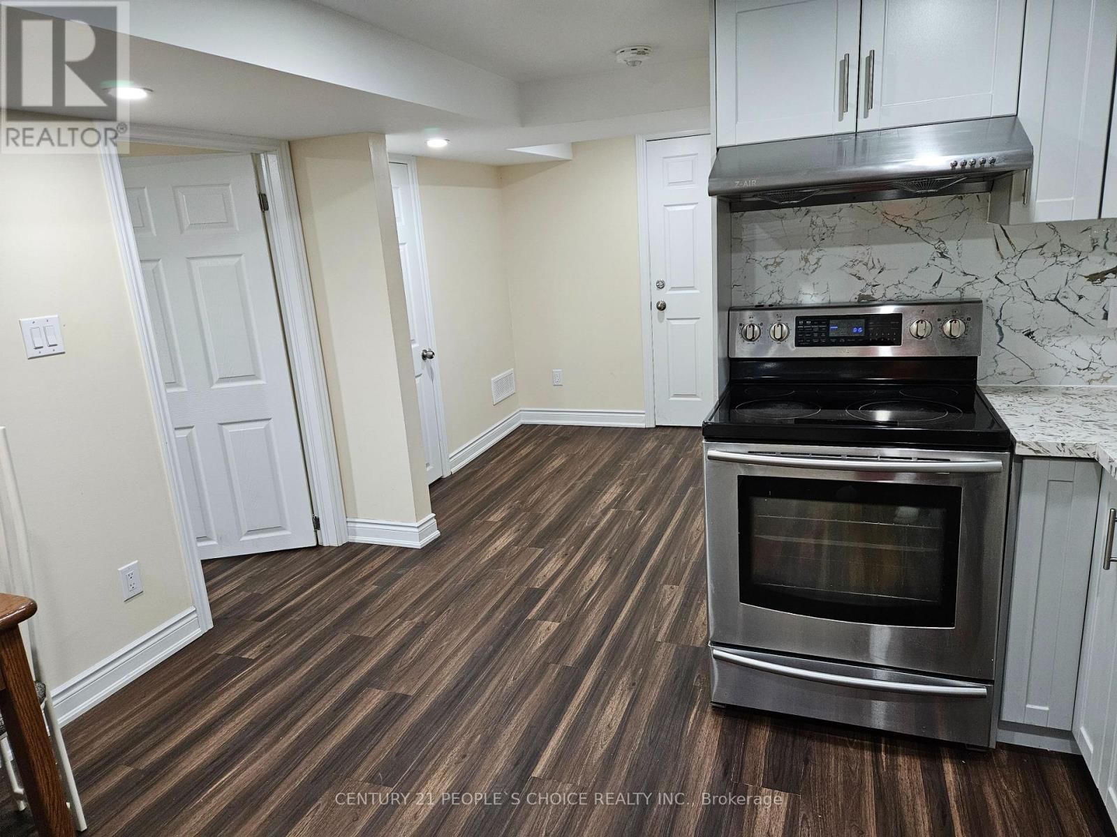 A kitchen with a stove top oven and wooden flooring.