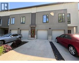 A two-story building with a garage and two cars parked in front.
