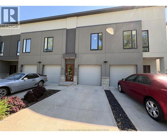 A two-story building with a garage and two cars parked in front.