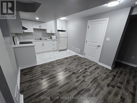 A kitchen with white cabinets and a wooden floor.