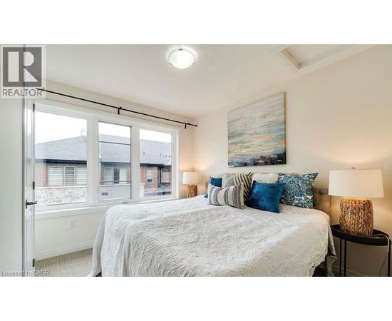 A bedroom with a large bed and a painting on the wall.