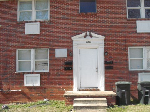 A red brick house with a white door and windows.