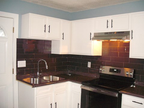 A kitchen with white cabinets and a black stove top oven.