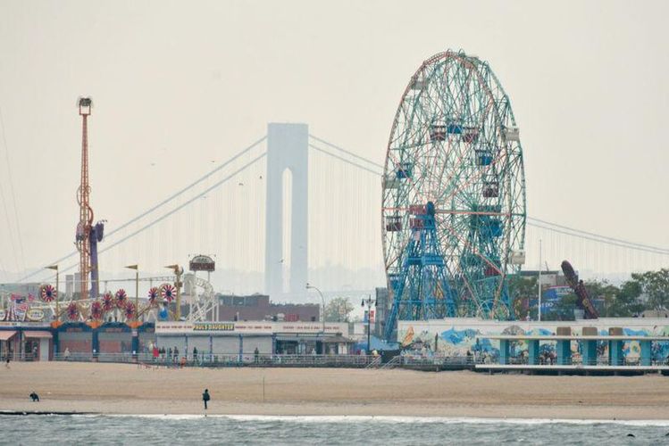 A Ferris wheel and a bridge are visible in the background of a beach scene.