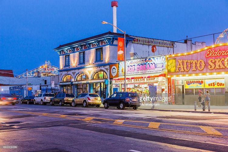 A busy street with cars and a building with a sign that says "Auto Shop".