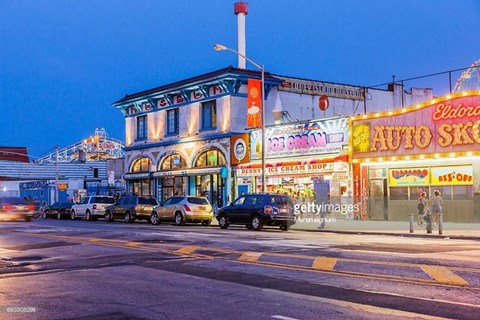 A busy street with cars and a building with a sign that says "Auto Shop".