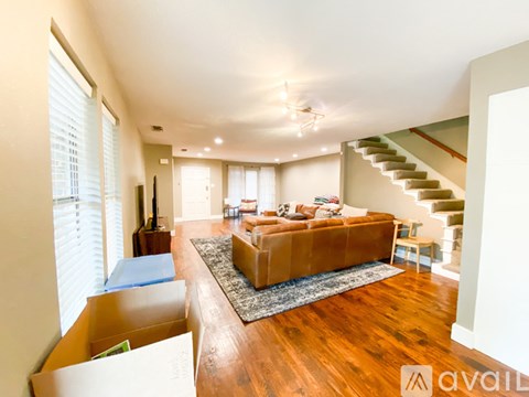 A living room with a brown couch and a staircase.