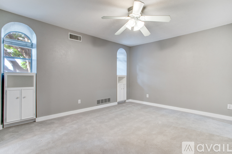 A spacious room with a ceiling fan and a window with a view of trees.