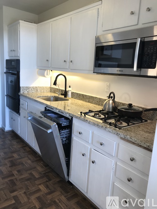 A kitchen with white cabinets and a granite countertop.