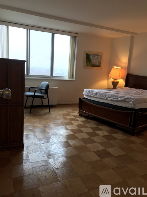 A bedroom with a bed, chair, and lamp.