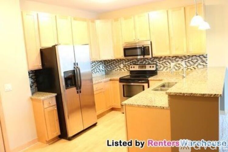 A kitchen with wooden cabinets and a black refrigerator.