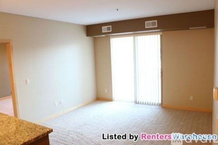 A room with a carpet floor and a window with blinds.