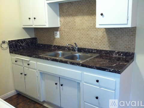 A kitchen with white cabinets and a black countertop.
