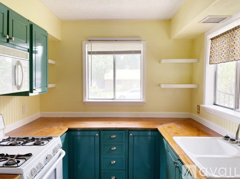 A kitchen with a white stove and green cabinets.