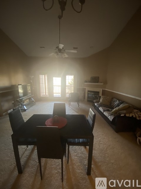 A dining room with a table and chairs is lit by sunlight coming through the windows.