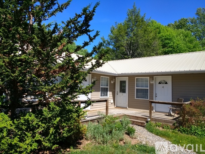 A house with a porch and a tree in front.