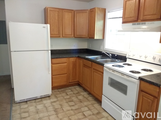 A kitchen with a white refrigerator, white stove, and wooden cabinets.