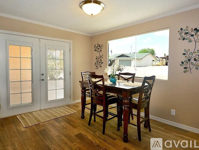 A dining room with a table and chairs and a window.
