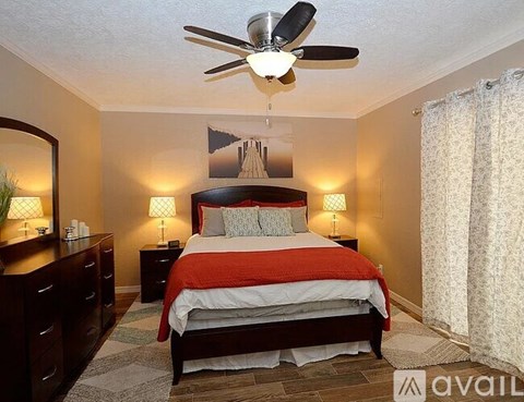 A bedroom with a bed, dresser, and a ceiling fan.
