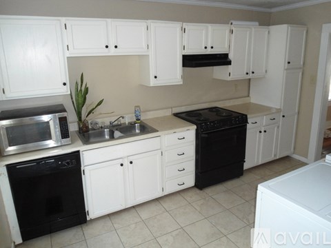 A kitchen with white cabinets and black appliances.
