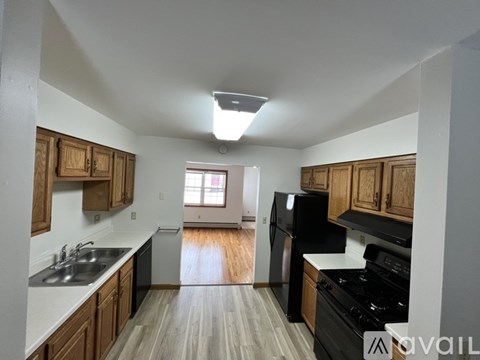 A kitchen with wooden cabinets and a black fridge.