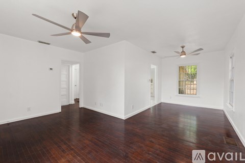 A room with a ceiling fan and hardwood floors.