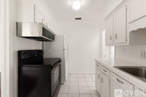 A kitchen with black appliances and white cabinets.