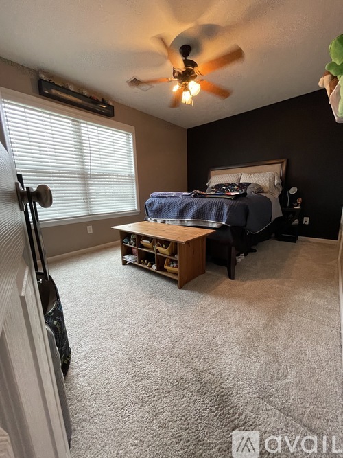 A bedroom with a bed, a ceiling fan, and a window with blinds.