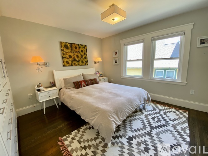 A bedroom with a large bed and a patterned rug.