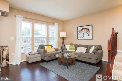 A living room with a couch, a chair, a coffee table, and a painting of a horse on the wall.