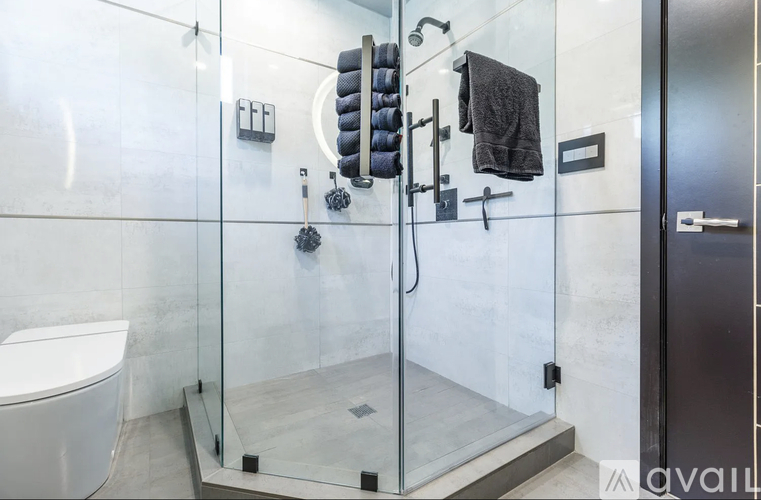 A modern bathroom with a glass shower stall and a toilet.