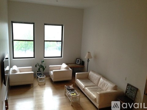 A living room with white furniture and a large window.