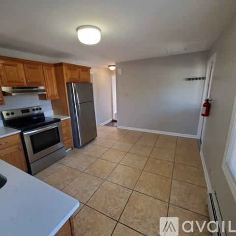 A kitchen with tile flooring and a refrigerator.