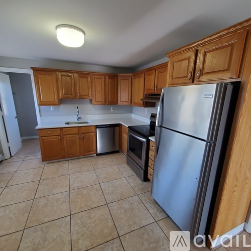 A kitchen with wooden cabinets and a stainless steel refrigerator.