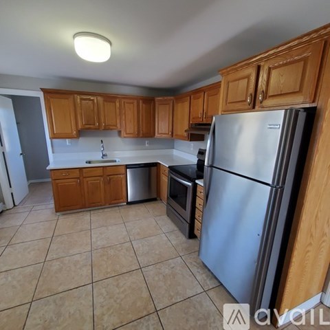 A kitchen with wooden cabinets and a stainless steel refrigerator.